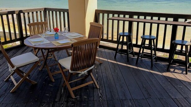 A wooden deck with a table set for dining, overlooking a turquoise sea. - Pontoon <ishigakijima> (Ishigaki)