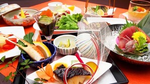 Une variété de plats japonais, notamment des sashimis, des sushis et un bol de soupe, disposés sur une table.