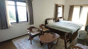 Ein Hotelzimmer mit einem Bett, zwei Stühlen, einem kleinen Tisch und einem Fenster.