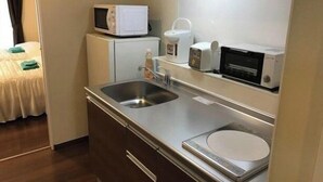 A compact kitchenette with a microwave, coffee maker, and toaster.