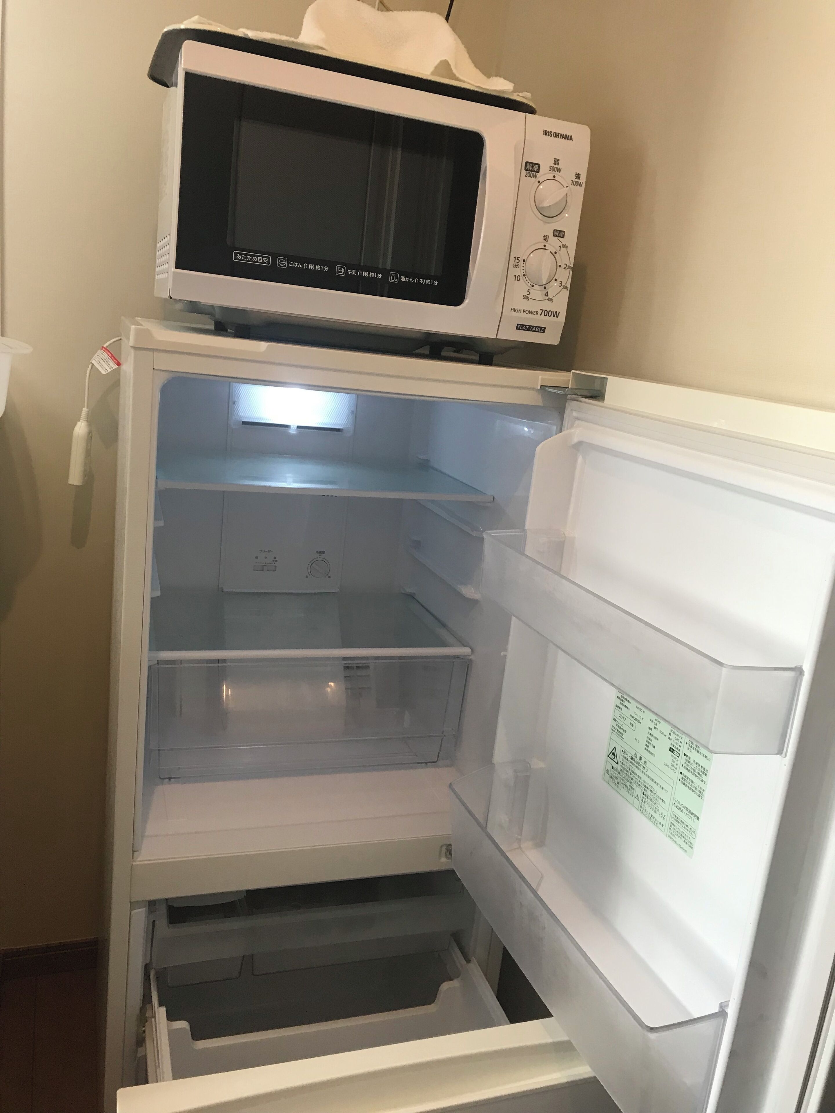 A refrigerator with a microwave on top, multiple transparent storage drawers, and a freezer compartment.