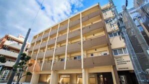 A multi-story hotel with a flat facade, multiple balconies, and a sign indicating it is a weekly hotel.