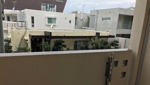 A view of a residential building with a beige exterior, a satellite dish, and a water tank on the roof.