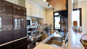 Een moderne keuken met roestvrijstalen apparatuur, een inbouwoven en diverse keukengerei en pannen op planken.