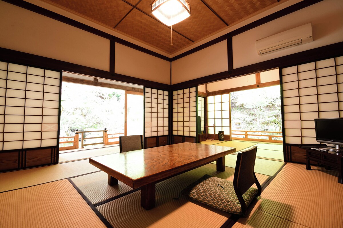 A traditional Japanese room with tatami flooring, a low table, a television, and sliding doors.