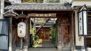 A traditional Japanese entrance with a wooden gate, a tiled roof, and a stone pathway leading to a building. - Tanba Sasayama Kinmata (Sasayama)