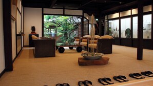 A traditional Japanese room with tatami flooring, a low table with a bowl, and a sofa with cushions. - Tanba Sasayama Kinmata (Sasayama)