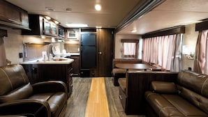 A compact RV interior with a kitchenette, seating area, and a dining table. - The Trailerhouse Village Yobuko Seaside (Karatsu)