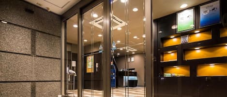 Uma área de recepção de hotel com portas de vidro, balcão de recepção e mesa de check-in.
