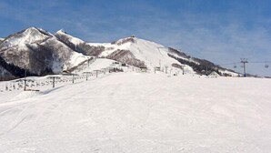 A snow-covered ski slope with a clear sky and mountains in the background. - Guest House Climb Dining (Yuzawa)