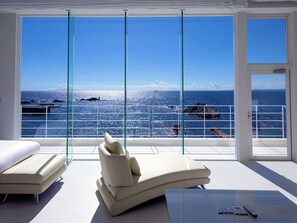 A modern room with a large glass window overlooking the sea, a comfortable lounge chair, and a small table. - Beach Terrace Boso (Futtsu)