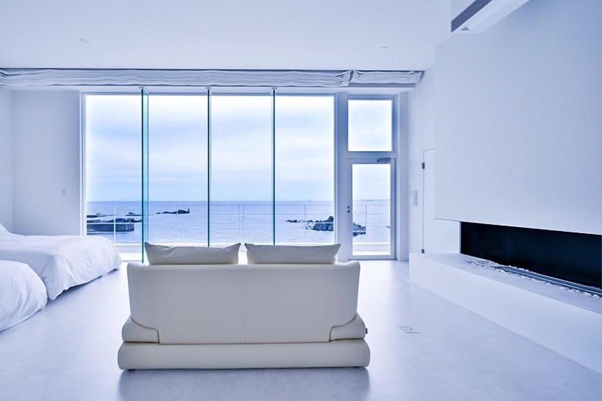 A modern hotel room with a large window offering a view of the sea.