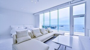 A modern bedroom with a large bed, a sofa, and a view of the sea. - Beach Terrace Boso (Futtsu)