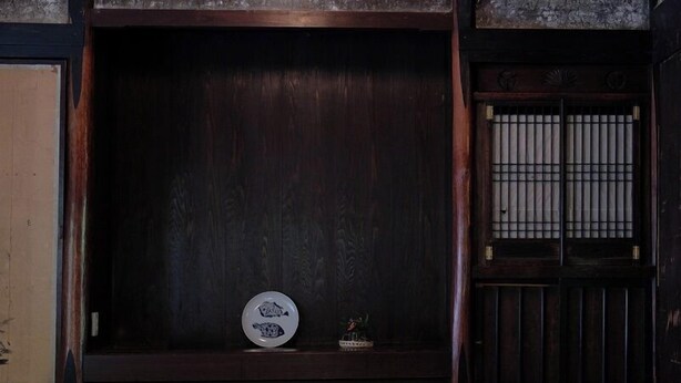 A traditional Japanese room with tatami flooring, a shoji screen door, and a small shelf with a decorative plate and a small plant. - Kasamatsutei (Aridagawa)