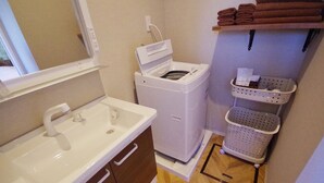A compact laundry area with a washing machine, a sink, and a drying rack. - Alezed Villa Shiraho <ishigakijima> (Ishigaki)