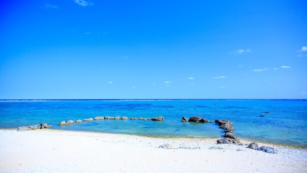 A beach with clear blue water, white sand, and a row of rocks leading into the sea. - Alezed Villa Shiraho <ishigakijima> (Ishigaki)