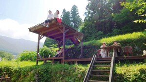 A wooden deck with a metal ladder, surrounded by lush greenery and a mountainous backdrop. - Farm Resort Awanowa (Mimasaka)
