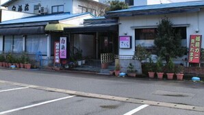 A building with a blue roof and a signboard with Japanese characters. - Shirahamaso (Fukui)
