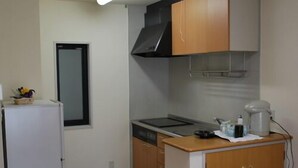 A compact kitchen with a refrigerator, stove, and cabinets. - Shirahamaso (Fukui)