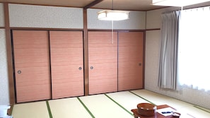 A traditional Japanese room with tatami flooring, sliding doors, and a low table with a bowl and chopsticks. - Yado Kashio (Toba)