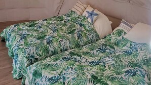 A room with two beds covered in tropical leaf-patterned bedding, a white wall, and a wooden floor. - Kakurega Shikinotsuki (Hokota)