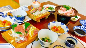Ett urval av rätter, inklusive sashimi, grönsaker och soppa, presenterade på ett träbord.