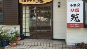 A building with a large glass door and a sign above it. There are potted plants outside. - Minshuku Kan (Tosashimizu)