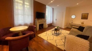 Un salon avec une cheminée, un téléviseur, une table ronde et un canapé.