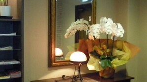 A wooden dresser with a mirror, a lamp, and a vase with white flowers. - Hotel Takako (Aizuwakamatsu)