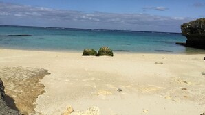 A beach with clear turquoise water, a sandy shore, and two prominent rocks in the middle. - Izumibaru House (Nakijin)