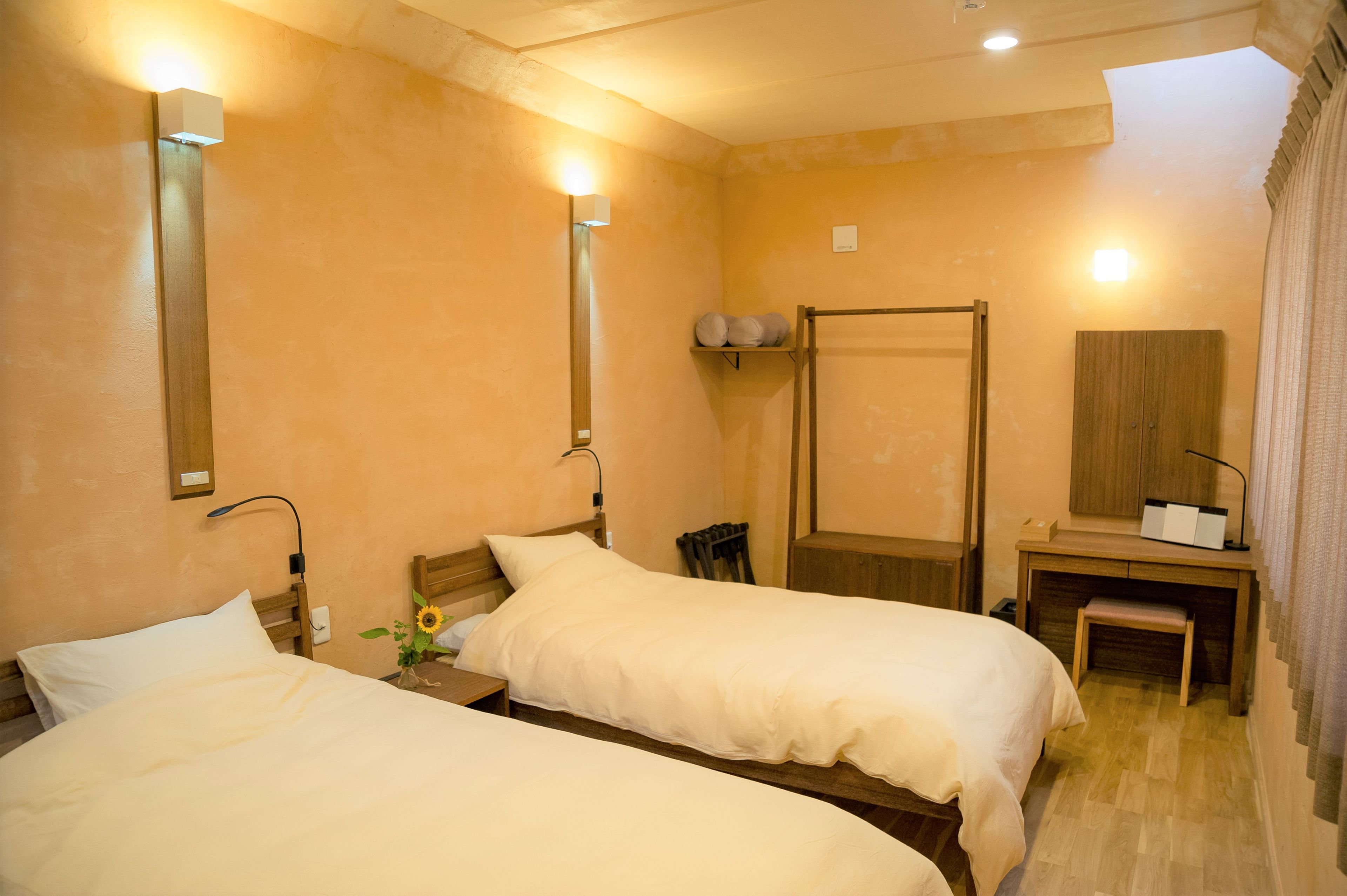 Habitación de hotel con dos camas, un escritorio, un espejo y ducha.