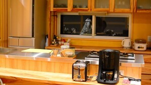 A kitchen with wooden cabinets, a stainless steel refrigerator, a coffee maker, and a toaster. - Izumibaru House (Nakijin)