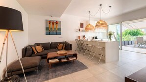 Un salon moderne comprenant un canapé, une table basse et un coin repas avec des chaises, ainsi qu’un comptoir de cuisine.