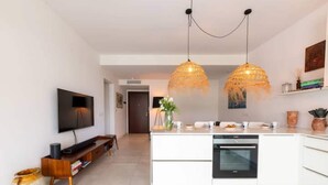 Une cuisine moderne dotée d’un îlot central, d’un four encastré et de luminaires suspendus.