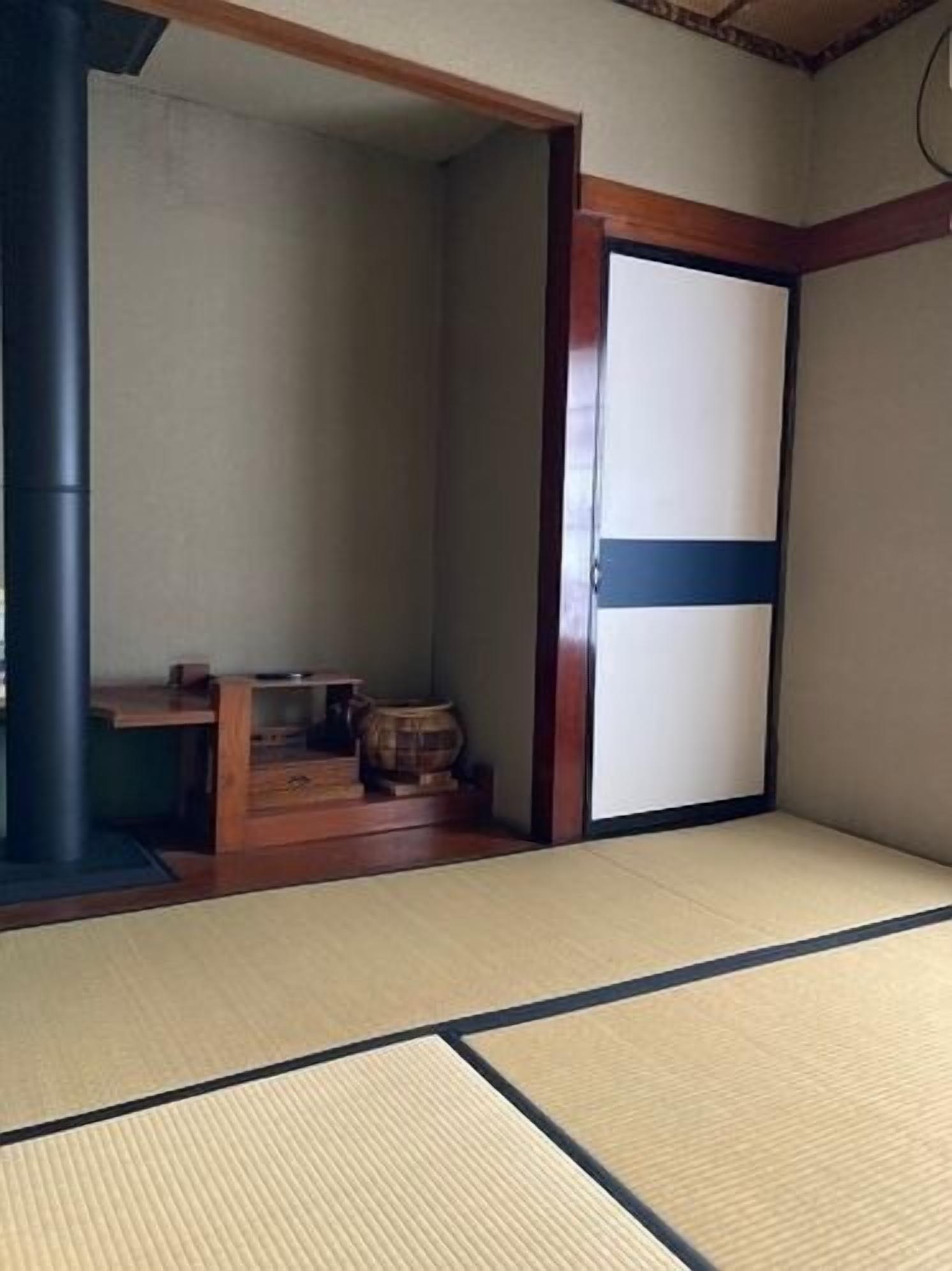 A tatami mat room with a sliding door, a wooden table, and a barrel.