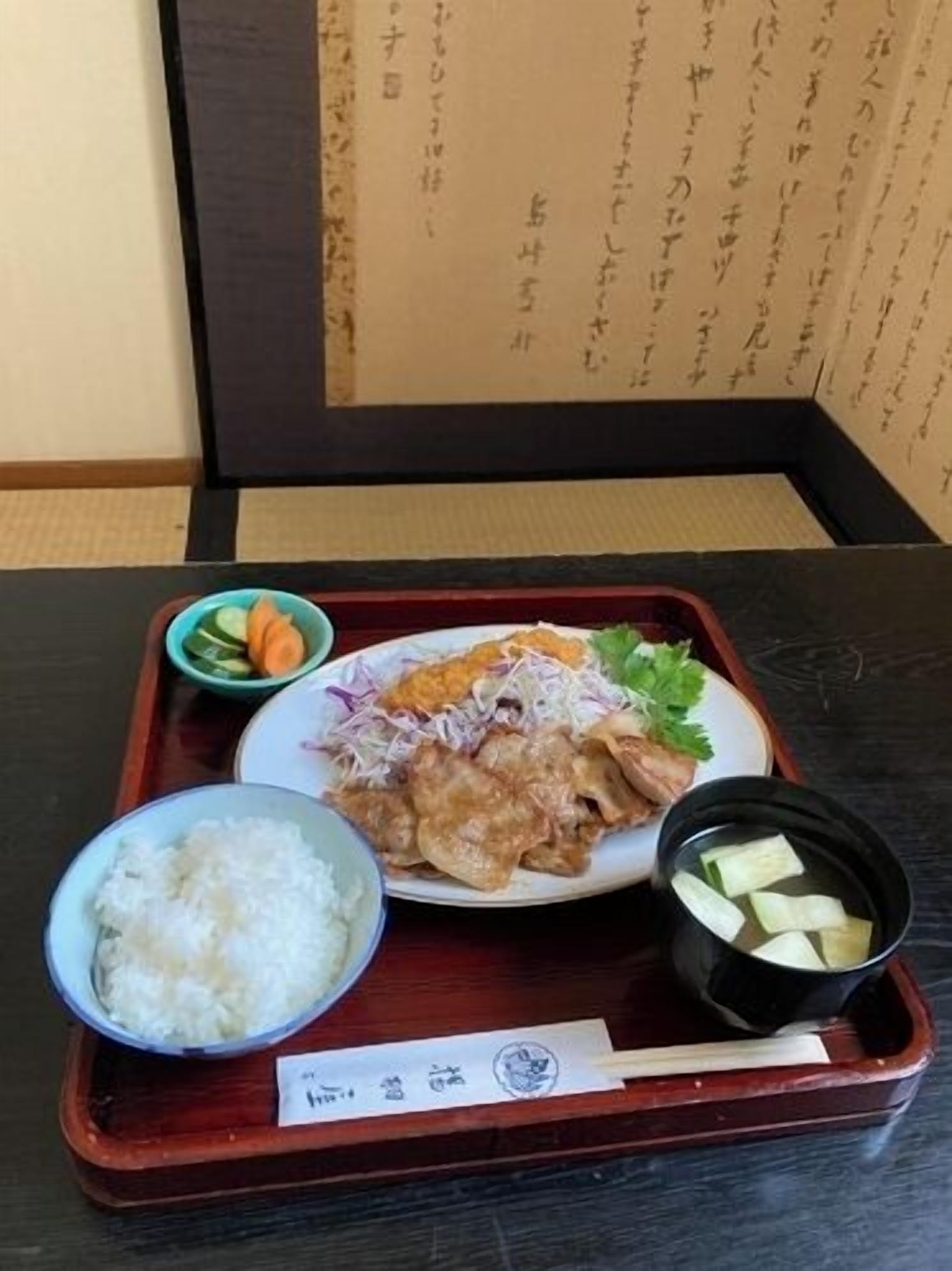 A traditional Japanese meal on a wooden tray, including rice, a bowl of soup, and a plate with various dishes.