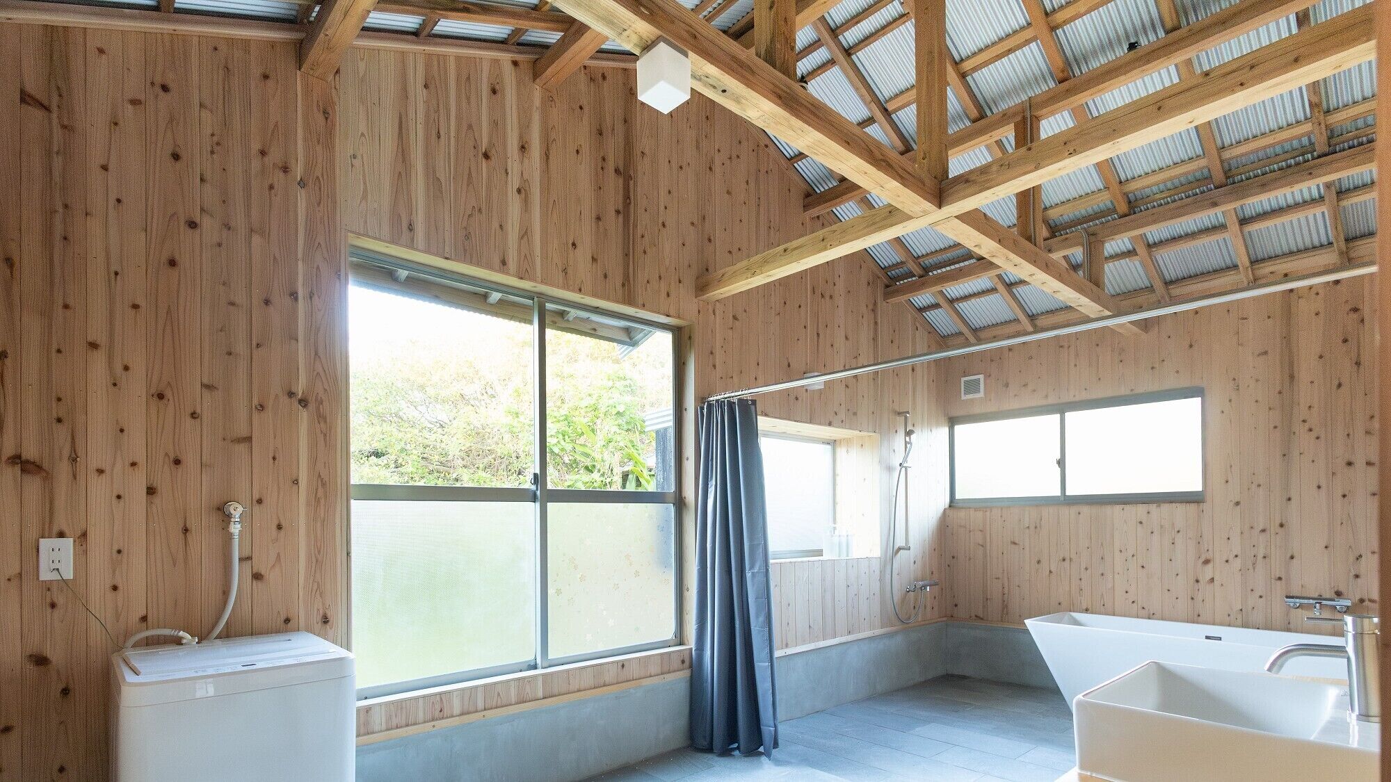 Een houten hut met een groot raam, een douche en een bad.