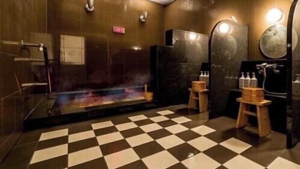 A modern bathroom with a checkered floor, a glass shower enclosure, and a wooden stool. - Super Hotel Saitama Kuki (Kuki)