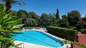 A swimming pool with lounge chairs, surrounded by greenery and trees. - Sea-View Duplex for Family (Villeneuve-Loubet)