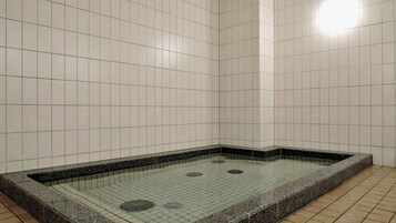 Un área de ducha con azulejos, un lavamanos rectangular y piso de azulejos.