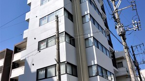 A multi-story hotel with a modern design, featuring a prominent entrance and a sign indicating it is a hotel. - Yukureba Maejima Hotel (Naha)
