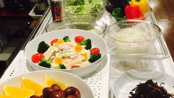 Una mesa de buffet con diversos alimentos, como ensaladas, frutas y verduras.