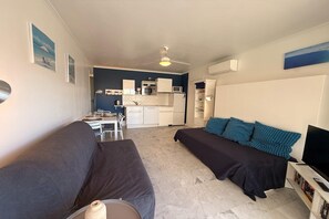 Ein kleiner Wohnbereich mit Küchenzeile, einer Couch, einem Bett und einem Fernseher.