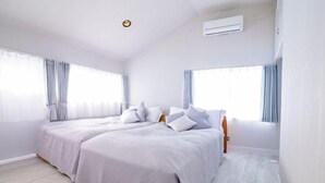 Un dormitorio moderno con dos camas, ventanas amplias y un equipo de aire acondicionado.