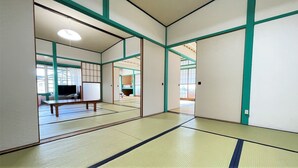 Habitación con suelo de tatami, puertas correderas, televisor y futón.