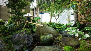 Un jardín japonés tradicional con disposición de rocas, bambú y abundante vegetación.
