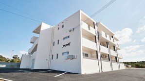 A modern white building with a sign reading "yuyuki" on the side. - Condominium Yuyuki (Yomitan)