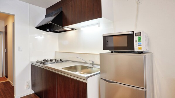 A modern kitchen with a built-in microwave, stainless steel appliances, and a sleek design. - Condominium Yuyuki (Yomitan)