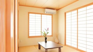 A traditional Japanese room with tatami flooring, a low wooden table, a vase with flowers, and sliding doors. - Palm Villa Ishigakijima Igusa (Ishigaki)