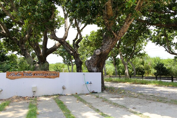 Une enseigne avec l’inscription « Palm Villa ISFIGAKIJA » et un tuyau d’eau fixé à un mur.